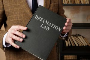 lawyer in suit holds defamation law book
