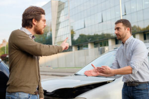 Two men arguing after a car accident on the road