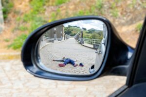 Fatal accident of a Pedestrian run over and lying dead on the road seen through the rearview mirror