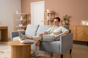 Injured young man after accident sitting on sofa at home