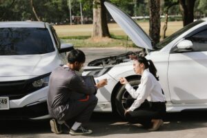 outdoor setting after a car accident, inspecting the vehicle for damage, discussing policy coverage, repair options, liability, and pursuing a claim.